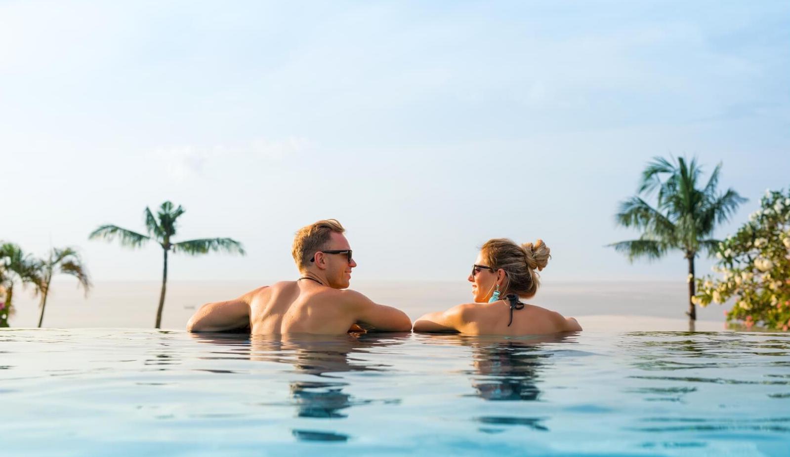 A man and a woman practicing mindfulness in a serene pool setting during their mindfulness retreats on an island.