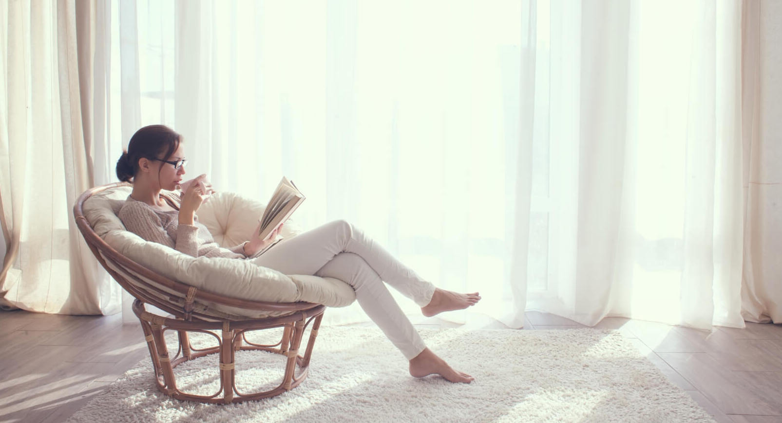 A woman sitting in a chair reading a book on emotional resilience and mindfulness practices.