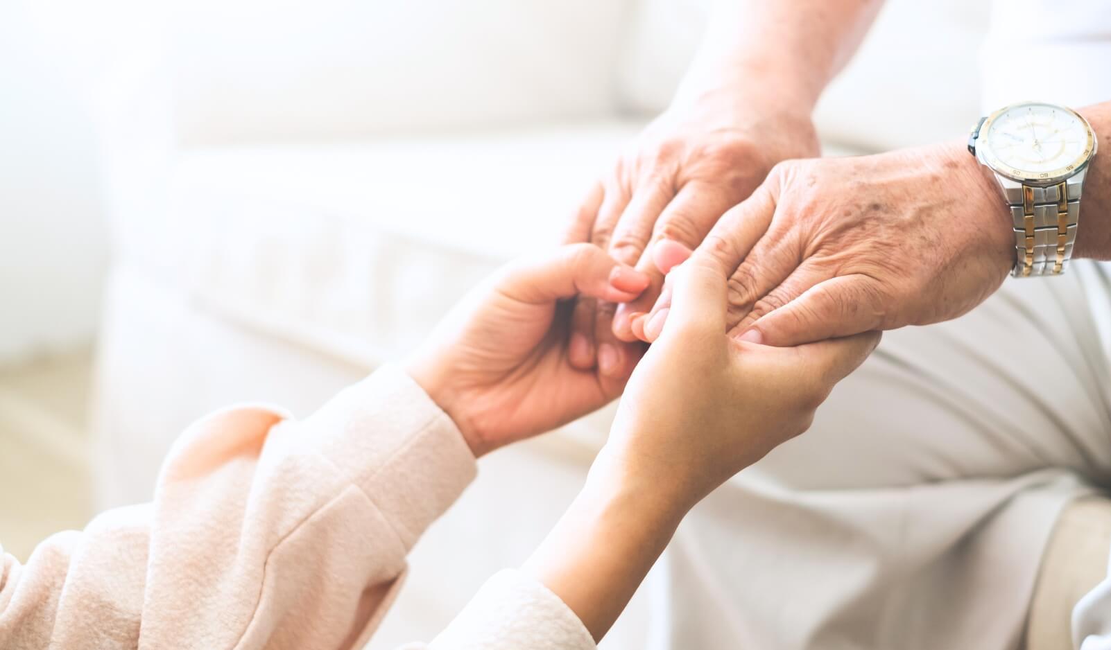 A young person compassionately holding a senior's hand to symbolize mindfulness and mental well-being for seniors.